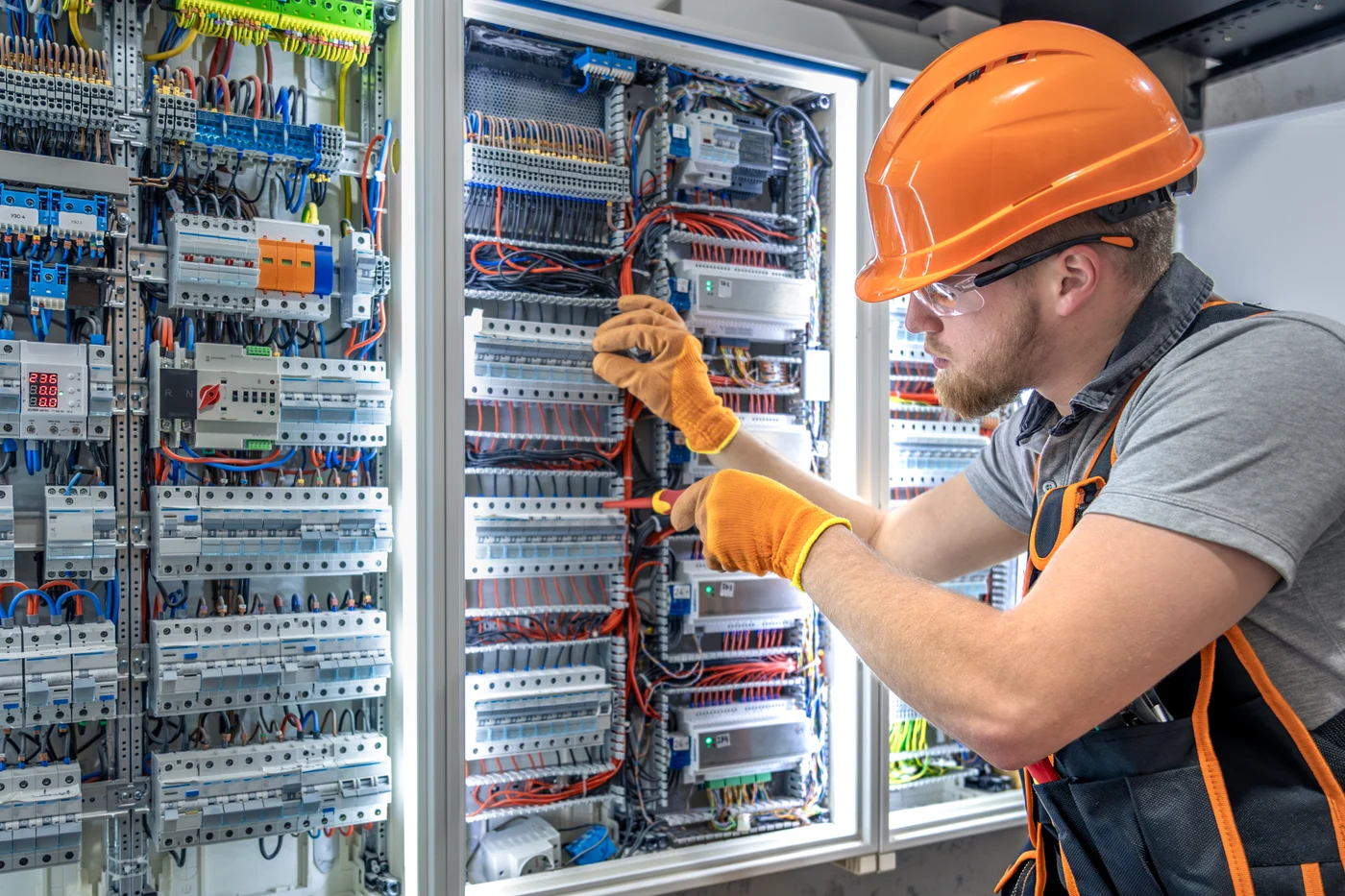 Elektriker mit Schutzhelm bei Installationsarbeiten an einem Schaltschrank